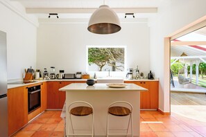 Una cocina moderna con armarios de madera, una isla central y un ventanal con vista a un árbol.