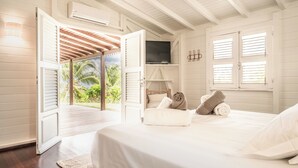 Ein Schlafzimmer mit Bett, Fernseher und Blick ins Freie.