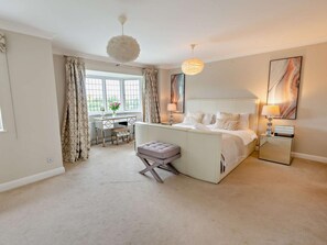 A bedroom with a bed, bedside tables, a desk, and a chair.