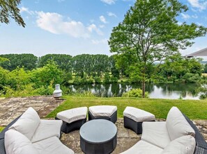 An outdoor seating area with wicker furniture and a view of a lake.
