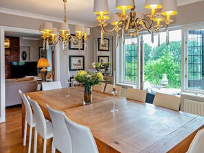 A dining area with a wooden table, white chairs, and a chandelier.