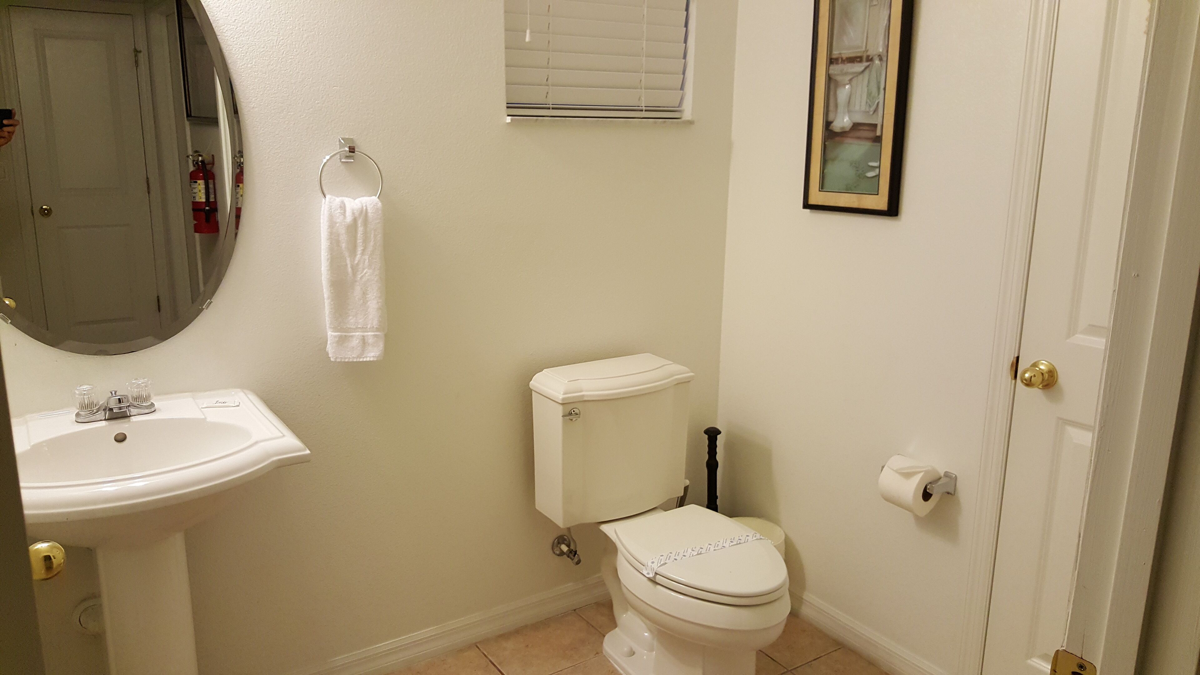 Un baño con lavamanos, inodoro y espejo blancos.