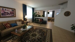 A living room with a sofa, coffee table, and patterned rug. There is a staircase leading to another room.
