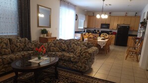 A living room with a sofa, coffee table, and a dining area with chairs and a table.