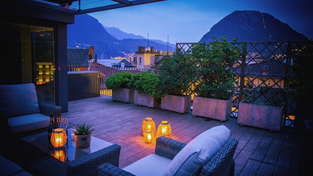 Una terrazza sul tetto con posti a sedere all'aperto, piante in vaso e vista sulla città e sulle montagne.