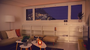 A modern living room with a city view, a sofa, a coffee table, a side table, and a bookshelf. - Luxury Nassa Penthouse With Private Terrace in Lugano (Lugano)
