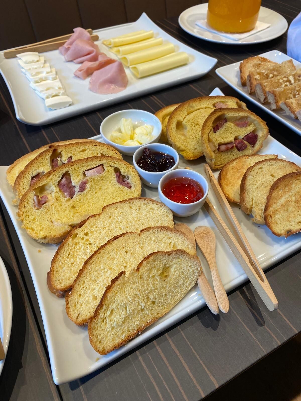 Una bandeja de desayuno con pan, jamón, queso y salsas.