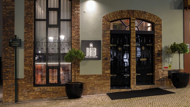 A brick building with two large arched doors and a sign reading "BHD". - BHB Boutique House (Macedo de Cavaleiros)