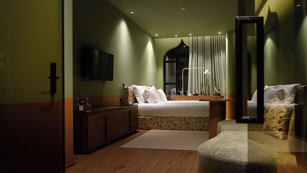 Ein modernes Hotelzimmer mit einem großen Bett, einem Schminktisch, einem Spiegel und einem Flachbildfernseher.