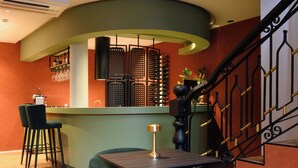 A bar area with a curved counter, black chairs, and a table with a lamp. - BHB Boutique House (Macedo de Cavaleiros)