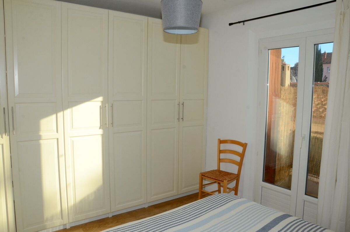 A bedroom with a bed, a chair, and a wardrobe.