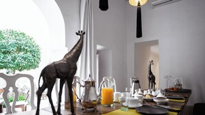 Ein Essbereich mit einem für das Frühstück gedeckten Tisch, darunter eine Giraffenfigur, ein Orangensaftkrug und verschiedene Frühstücksartikel.