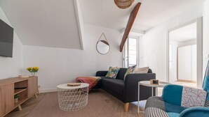 A modern living room with a sofa, a coffee table, a side table, a wooden cabinet, and a hanging mirror. - Penthouse Center (Vigo)