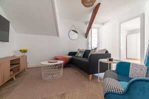 A modern living room with a sofa, a coffee table, a side table, a wooden cabinet, and a hanging mirror.