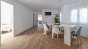 A modern dining area with a white table, four chairs, and a potted plant. - Penthouse Center (Vigo)