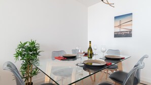 Ett modernt matområde med ett glasbord, svarta stolar och en krukväxt.