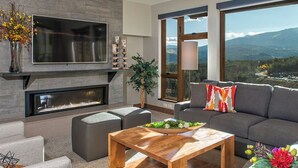 A modern living room with a fireplace, a large flat-screen TV, a sofa, and a view of mountains through large windows. - Grand Colorado on Peak 8 Resort in Breckenridge
4 Bedroom will consider 2/3 Bdrm (Breckenridge)