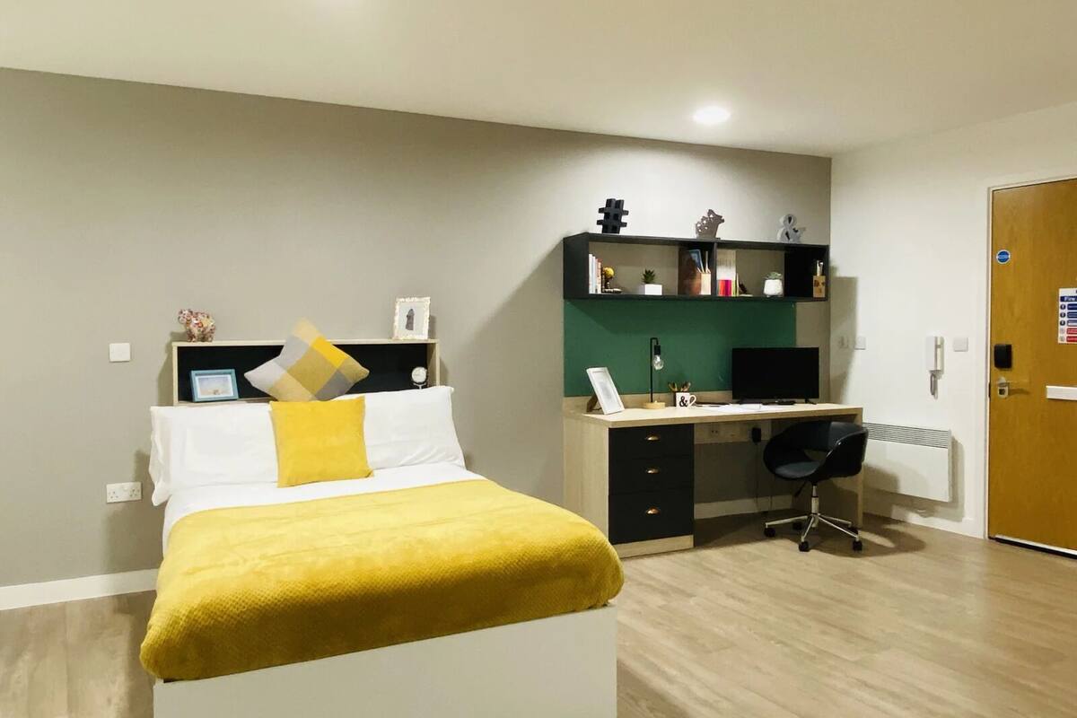 A bedroom with a bed, a desk, and a chair.