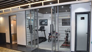 Academia moderna com paredes de vidro, esteira e diversos equipamentos de ginástica.