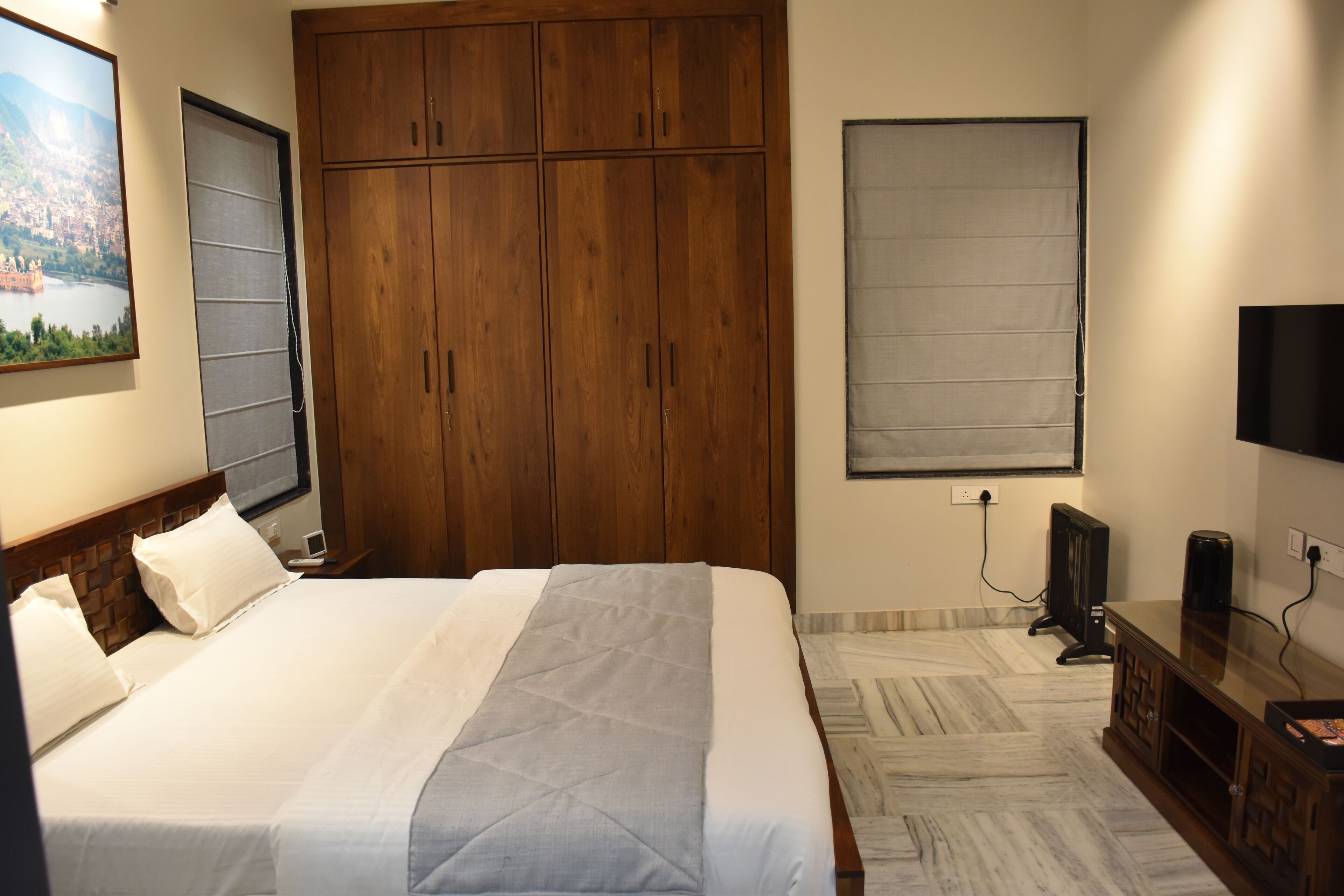Ein Hotelzimmer mit einem großen Bett, einem Holzschrank, einem Fernseher und einem Bild an der Wand.