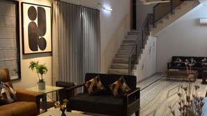 Uma sala de estar moderna com sofá, mesa de centro e escada que leva a um andar superior.