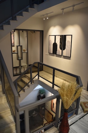 Ein modernes Interieur mit Glastrennwand, einer Vase mit Trockenblumen und Kunstwerken an der Wand.
