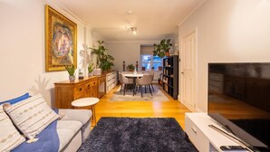 Ein modernes Wohnzimmer mit einer Couch, einem Couchtisch, einem Fernseher und einem Essbereich mit Tisch und Stühlen.