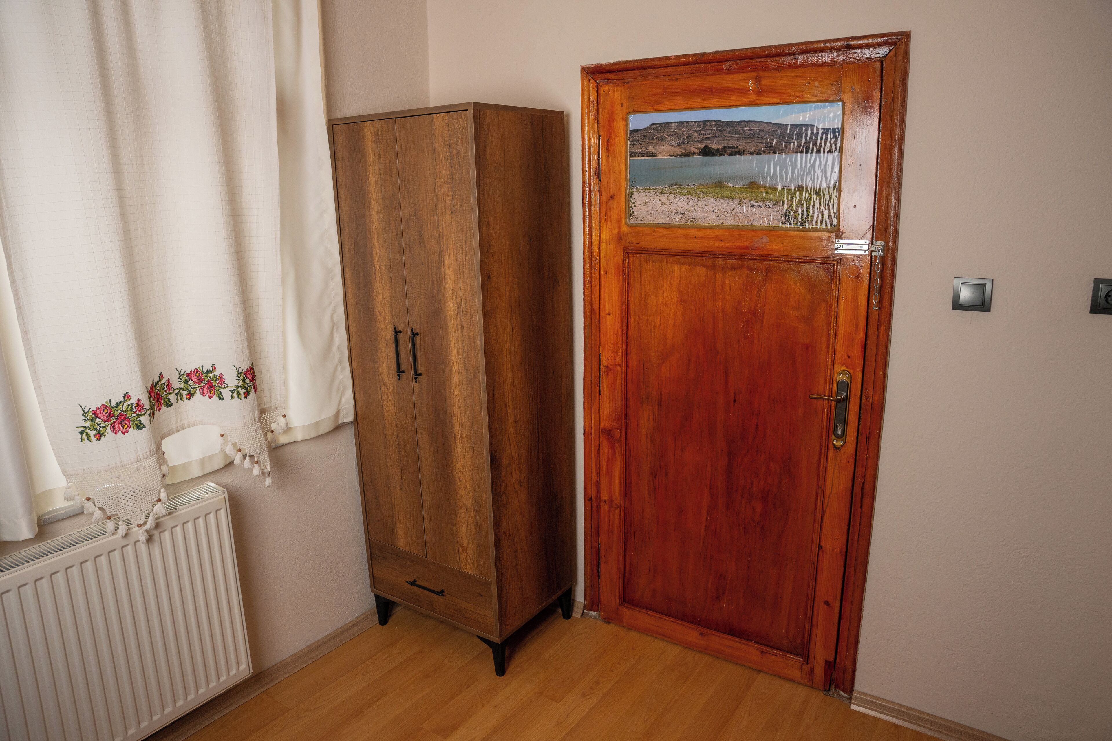 Un armario de madera, una puerta con vistas al paisaje y un radiador.
