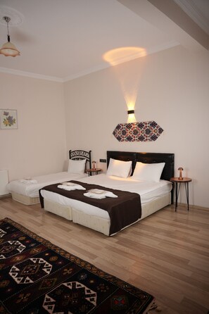 A bedroom with a large bed, two bedside tables, a patterned wall hanging, and a decorative floor lamp. - Colina Stone House (Ürgüp)