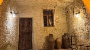 A stone-walled room with a wooden door, a small window, and two wall-mounted lights. - Colina Stone House (Ürgüp)