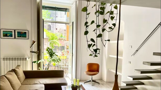 A modern living room with a sofa, coffee table, and hanging plants.