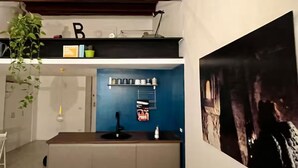 A modern kitchen with a blue accent wall, a wooden ceiling, and a large black and white artwork on the wall.