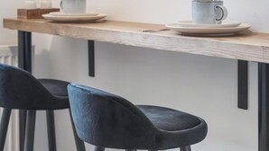 Un café au décor minimaliste, avec une table en bois, deux chaises noires et un mur blanc.