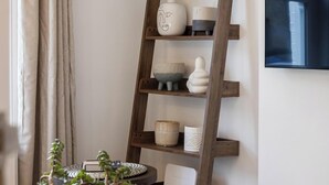 Une étagère en forme d’échelle en bois, agrémentée de divers objets décoratifs et d’une plante en pot.
