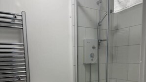 Un baño con inodoro, ducha con cerramiento de vidrio y un perchero para toallas.