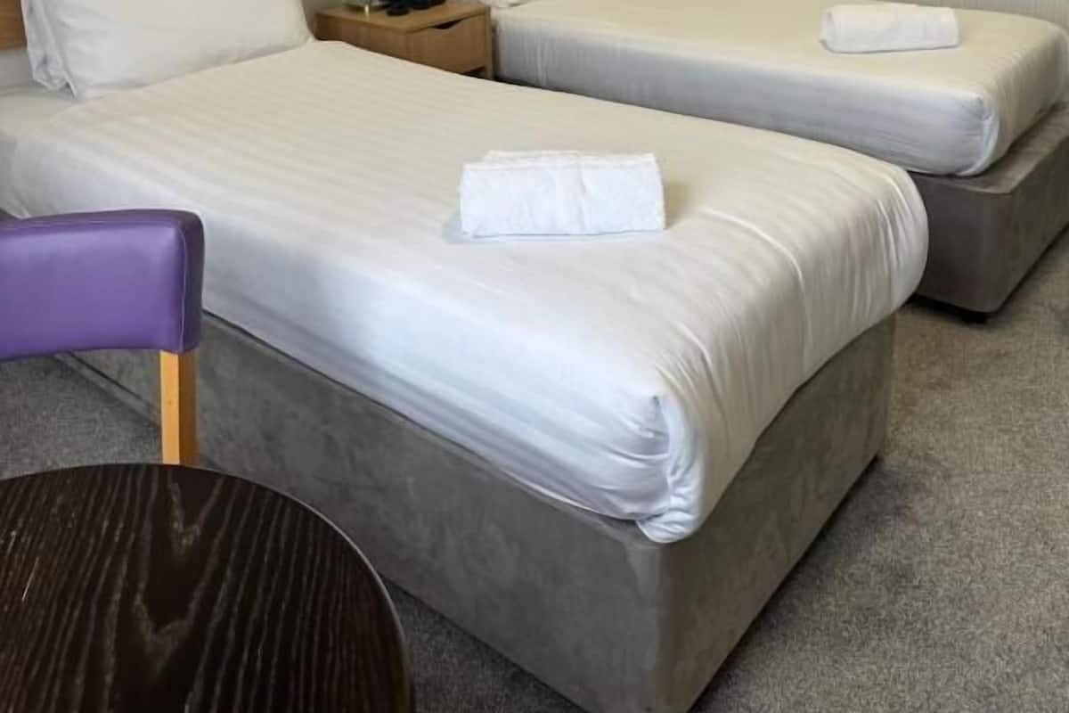 Habitación de hotel con dos camas, una mesita y una silla.