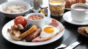 Un plato de desayuno con huevos, salchichas, tocino, champiñones y frijoles.