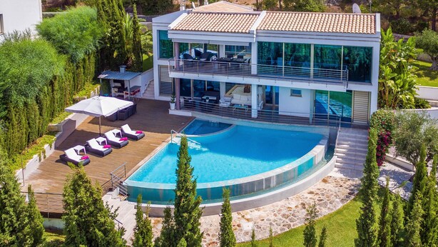 Ein modernes, zweistöckiges Haus mit Swimmingpool, Sitzgelegenheiten im Freien und einem üppigen Garten.