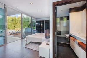 Una camera da letto moderna con un letto grande, un comodino e vista su un balcone con mobili da esterno.