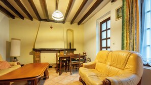 A cozy living room with a wooden table, a leather sofa, and a fireplace. - On The Rocks - Alpes Mancelles - Jardin (Sillé-le-Guillaume)