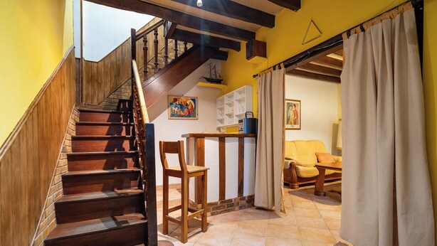 A wooden staircase leading to a landing with a dining area and a sofa. - On The Rocks - Alpes Mancelles - Jardin (Sillé-le-Guillaume)