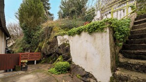 A stone staircase leading up to a white wall with greenery growing on it. - On The Rocks - Alpes Mancelles - Jardin (Sillé-le-Guillaume)