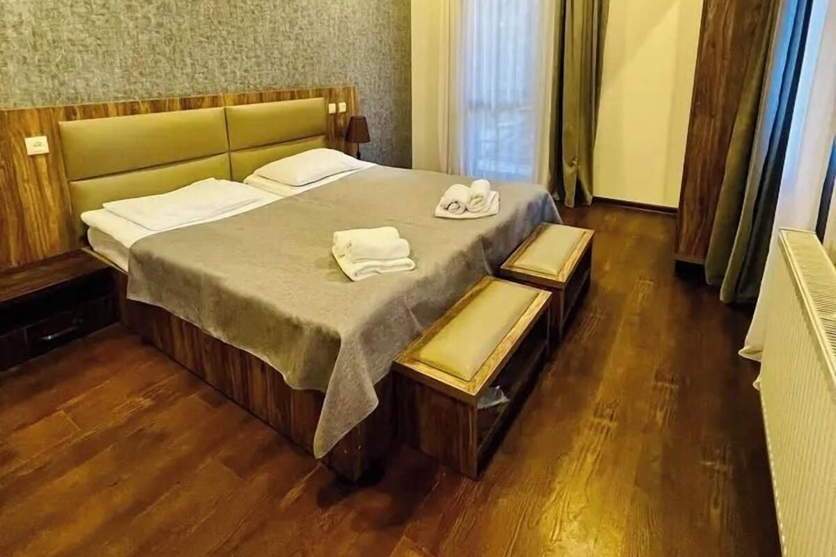 Ein Hotelzimmer mit einem großen Bett, einem Holzkopfende und einer Bank am Fußende.