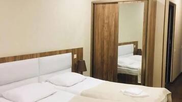 Een hotelkamer met een tweepersoonsbed, een houten garderobe, een spiegel en een nachtkastje.