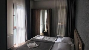 Ein Hotelzimmer mit zwei Betten, einem Kleiderschrank und einem Spiegel.