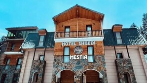 Ein zweistöckiges Holzgebäude mit Steinverkleidung, mit der Aufschrift "HOTEL SHGEDI MESTIA".