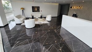 A modern lobby with a reception desk, seating area, and a large abstract painting on the wall. - Granda Centeno Luxury Studio (Quito)