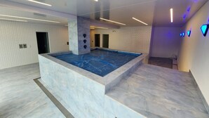 A modern indoor swimming pool with a marble floor and walls, surrounded by a minimalist design with recessed lighting. - Granda Centeno Luxury Studio (Quito)
