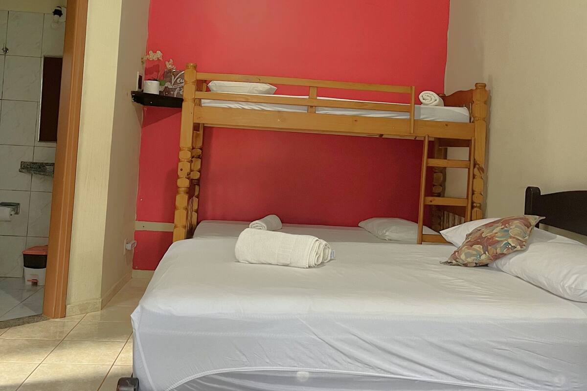 Une chambre avec un lit superposé, un mur rouge et une tête de lit en bois.