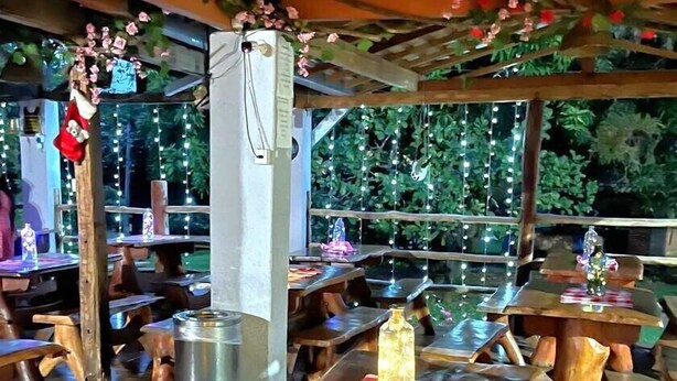 An outdoor dining area with wooden tables and benches, surrounded by greenery and string lights. - Hotel Fazenda Aguas VIvas (Pirenópolis)